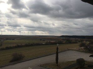 Paisaje rural con campos, una turbina eólica y una carretera.