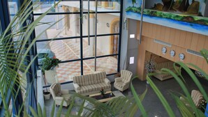 A lobby with a checkered floor, a large window, and a mural on the wall. - Hotel Los Barruecos (Malpartida de Caceres)