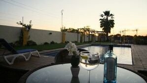Escena junto a la piscina con una mesa de vidrio, una botella y un vaso de agua.