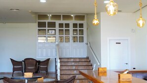 A hotel lobby with wicker furniture, a staircase, and a reception desk. - Hotel Los Barruecos (Malpartida de Caceres)