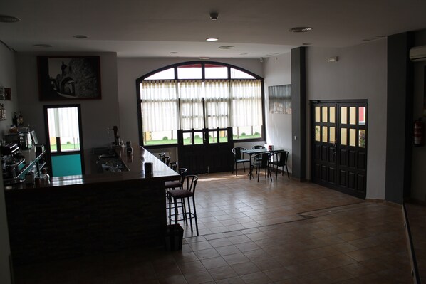 A spacious room with a large window, a bar area, and a dining table with chairs. - Hotel Los Barruecos (Malpartida de Caceres)