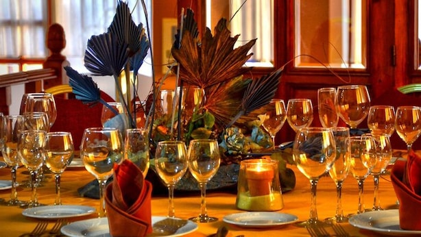A table set for dining with multiple wine glasses and plates, a candle centerpiece, and decorative foliage. - Hotel Los Barruecos (Malpartida de Caceres)