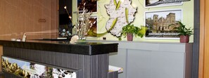 A reception desk with a map and a framed photo of a historic building. - Hotel Los Barruecos (Malpartida de Caceres)