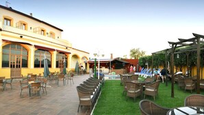 An outdoor patio with wicker furniture and a grassy area. - Hotel Los Barruecos (Malpartida de Caceres)