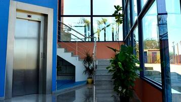 Entrada moderna de un edificio con escaleras, una puerta y plantas en macetas.