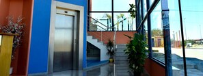 A modern building entrance with a staircase, a door, and potted plants. - Hotel Los Barruecos (Malpartida de Caceres)