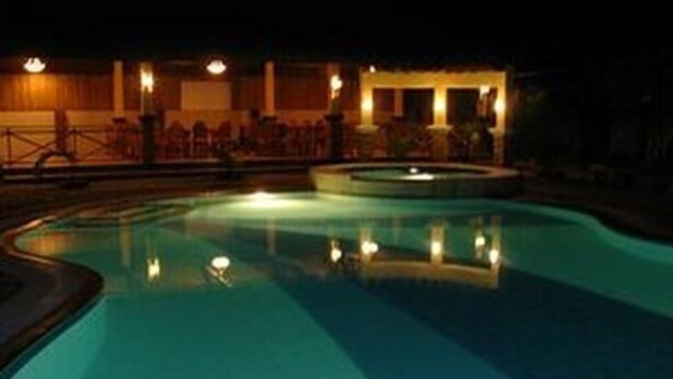 Ein Schwimmbad bei Nacht, mit im Wasser glänzenden Lichtern.