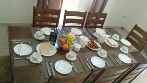 Una mesa de comedor dispuesta con platos, cubiertos y un frutero.