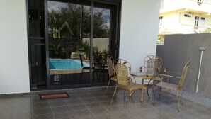 Un patio con piscina, mobiliario exterior y vista a un edificio al fondo.