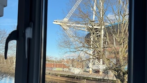 A view of a Ferris wheel, a body of water, and a tree through a window. - WiseStay (Cardiff)