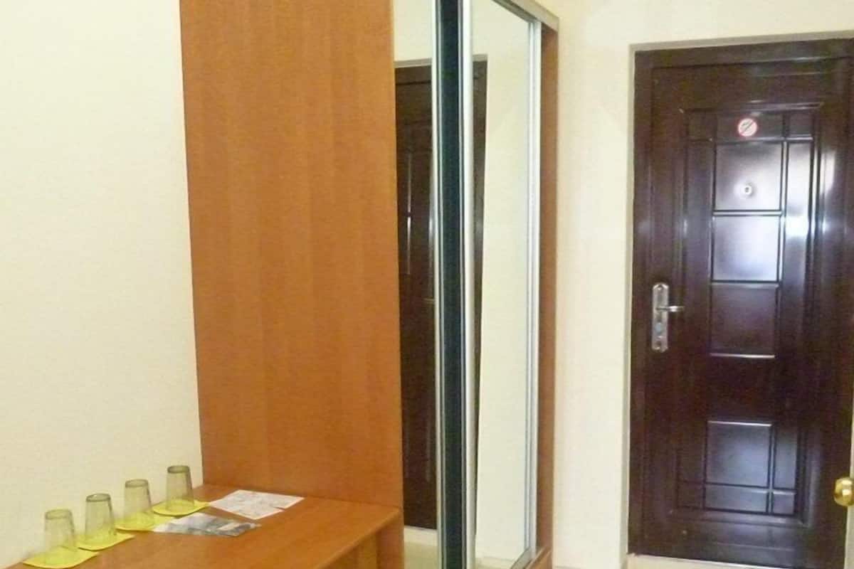 A room with a wooden dining table, four chairs, a sliding glass door, and a dark wooden door.