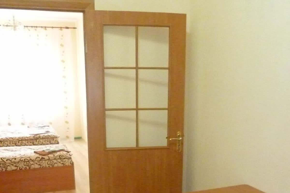 A room with a wooden door, a small table, and two wooden stools.