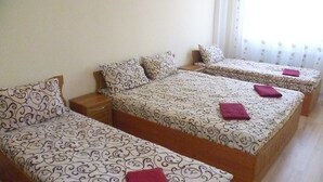 Une chambre d’hôtel avec trois lits simples, chacun agrémenté d’une couvre-lit à motifs et de coussins.