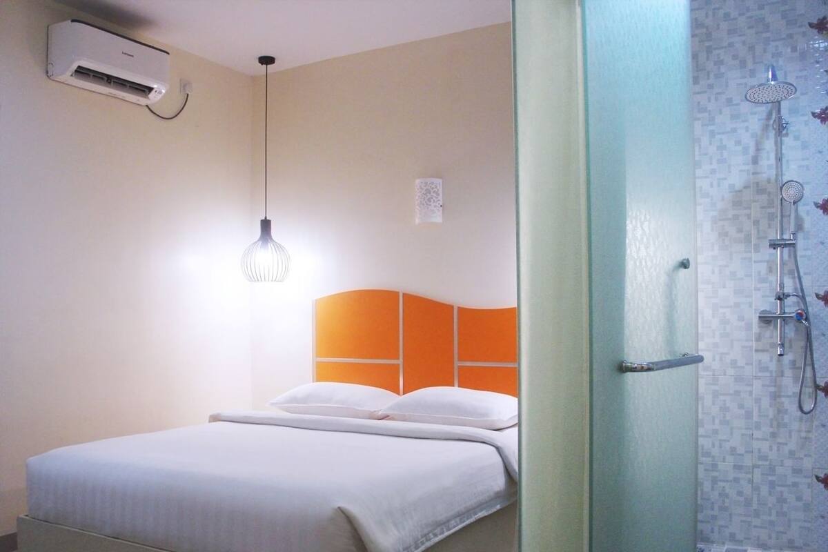 Een hotelkamer met een bed, een airconditioner, een hanglamp en een douche.