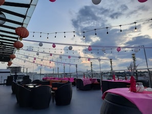 Un espace extérieur aménagé avec des tables et des chaises, des guirlandes lumineuses et des lanternes suspendues.