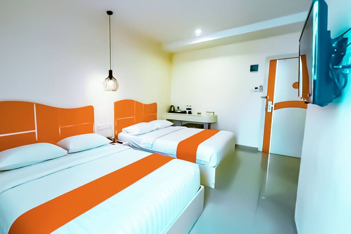 Een hotelkamer met twee bedden, een nachtkastje, een spiegel en een hanglamp.