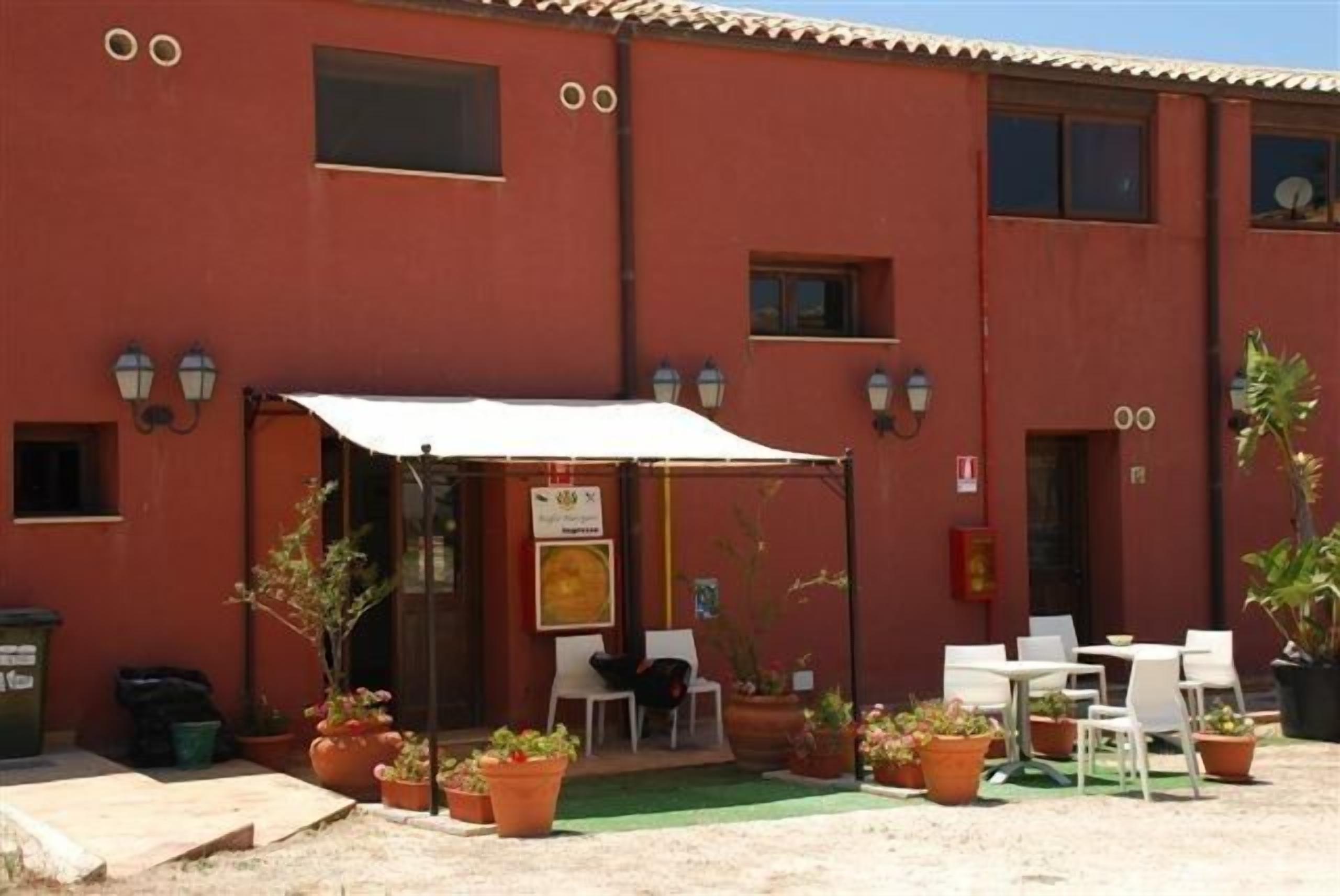 Un bâtiment rouge doté d’un patio, d’un espace extérieur aménagé avec des sièges et de plantes en pot.