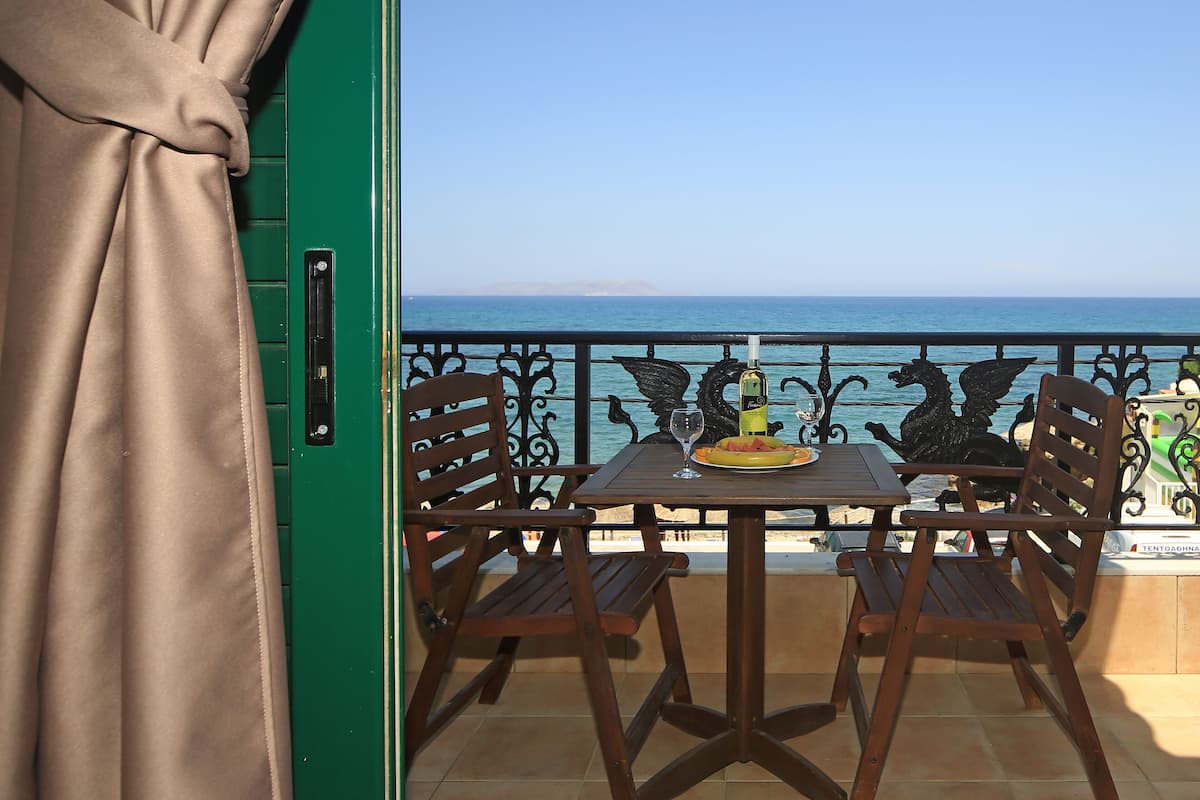 Un balcon avec une table et des chaises, une bouteille de vin et une assiette de nourriture.