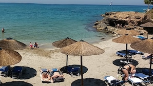 Une plage avec des parasols en chaume et des chaises longues.