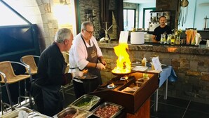 Un buffet proposant une variété de plats et une station de cuisson centrale avec des flammes.