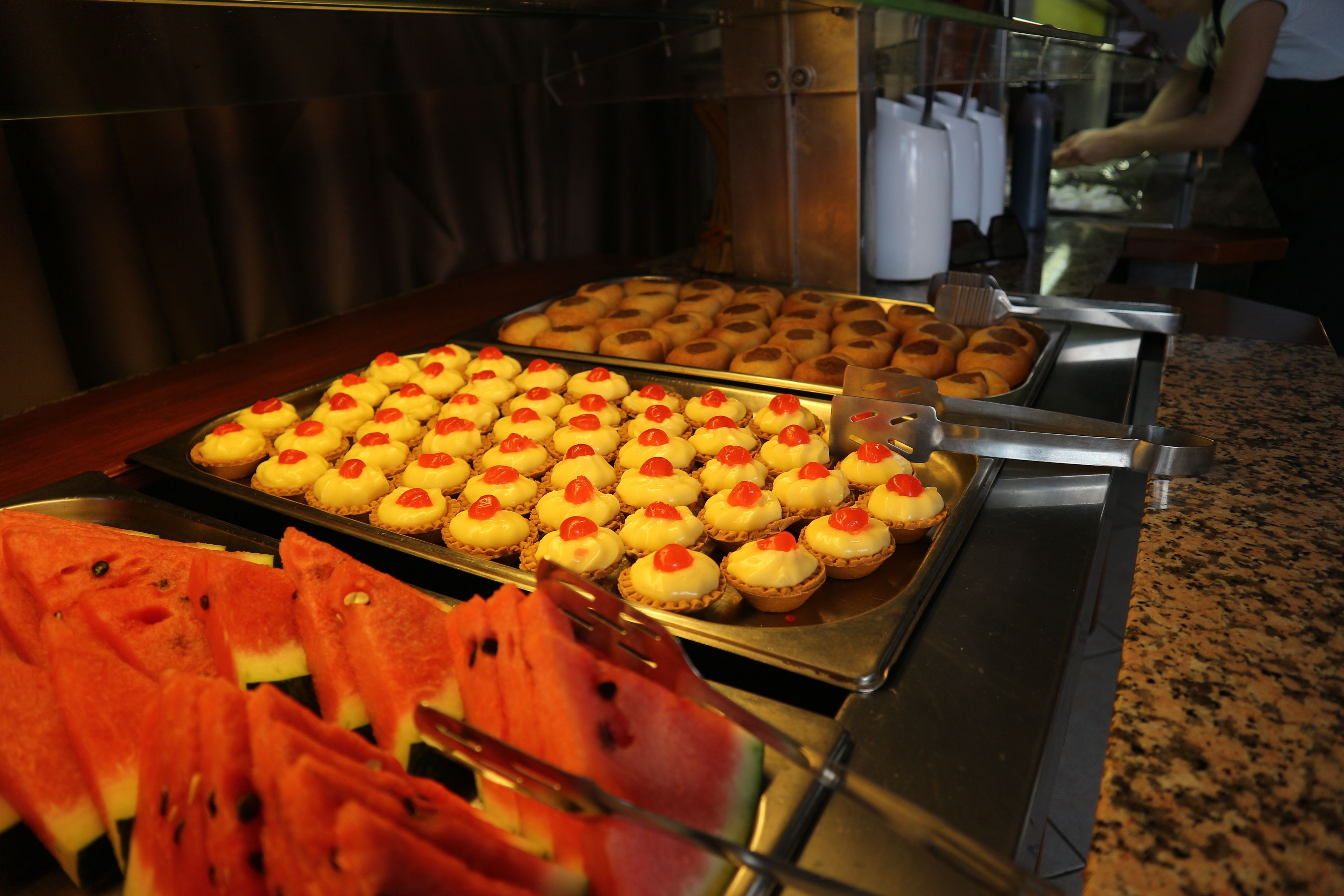 A buffet with various food items including cupcakes and watermelon slices.