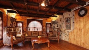 A cozy room with a wooden ceiling, a large window with a decorative frame, and a rustic wall with a clock. - Tuado Hotel (Baku)