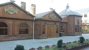 A traditional wooden building with arched windows and a sign that reads "TUADO Hotel & Restaurant." - Tuado Hotel (Baku)