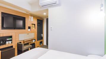 A hotel room with a bed, a TV, a coffee machine, and a small desk.