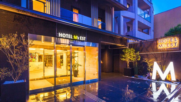 Un hôtel moderne doté d’une façade en verre, d’un grand panneau en forme de « M » bien visible et d’une entrée bien éclairée.