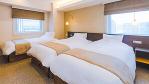 Une chambre d’hôtel avec deux lits, une fenêtre, une lampe fixée au mur et une vue sur la ville.
