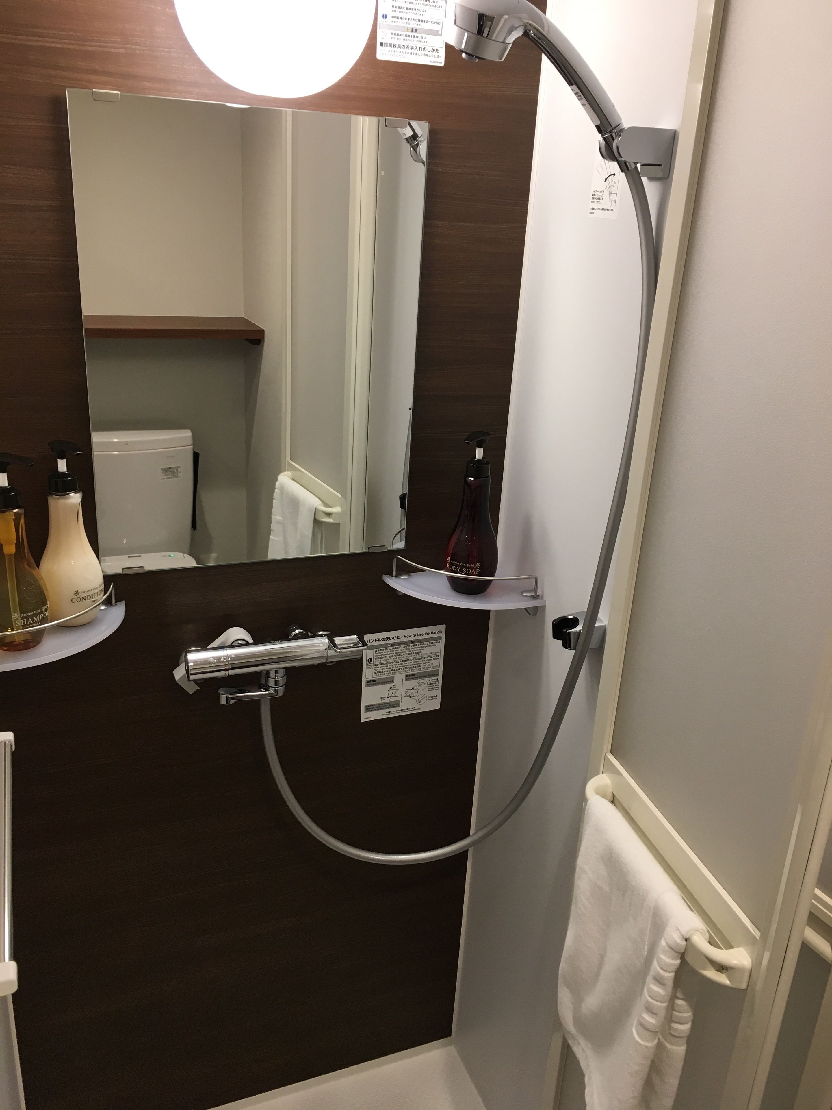 A bathroom with a dark wood vanity, a mirror, a towel rack, and a shelf with toiletries.