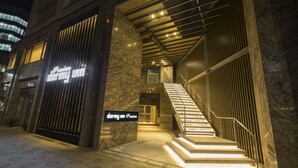 Entrada de hotel con fachada de mármol, una escalera y un cartel que indica un nivel premium.