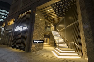 Entrada de hotel con fachada de mármol, una escalera y un cartel que indica un nivel premium.