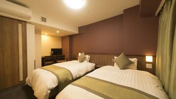 A hotel room with two beds, a television, and a wall-mounted light.