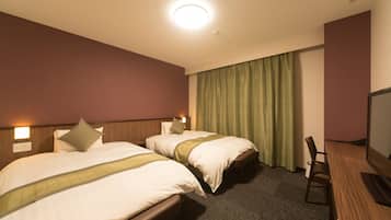 A hotel room with two beds, a desk, and a television.