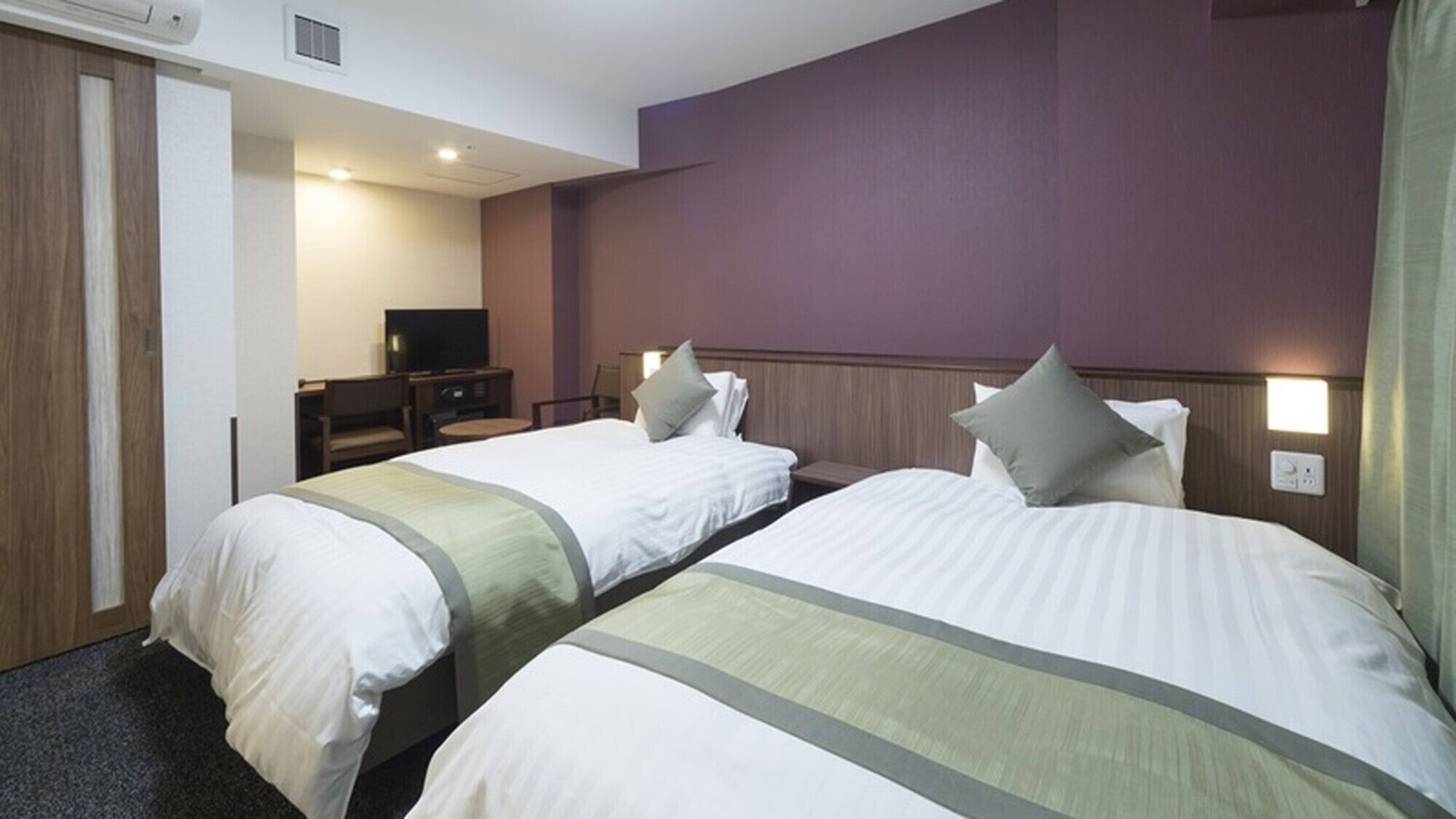 Una habitación de hotel con dos camas, televisión y escritorio.