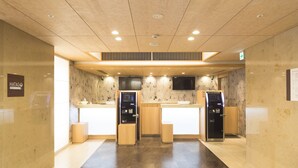Un moderno vestíbulo de hotel con un mostrador de recepción, una máquina expendedora y un televisor montado.