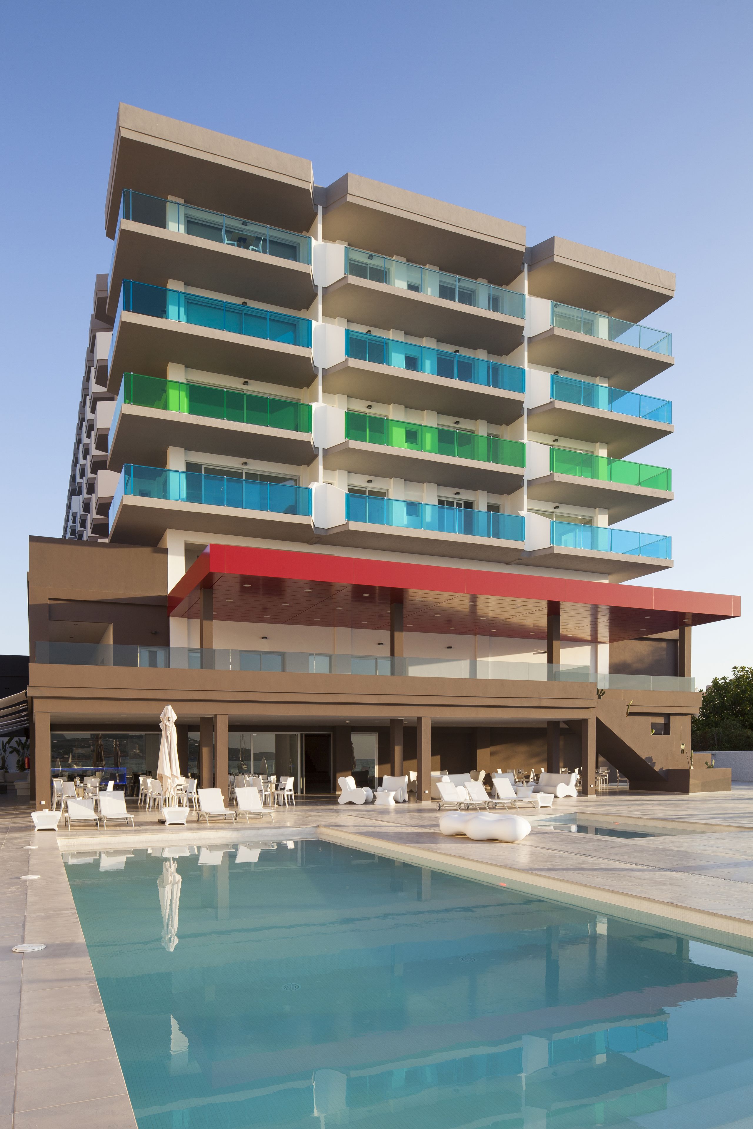 Un hotel a più piani con piscina, sedute all'aperto e balconi.