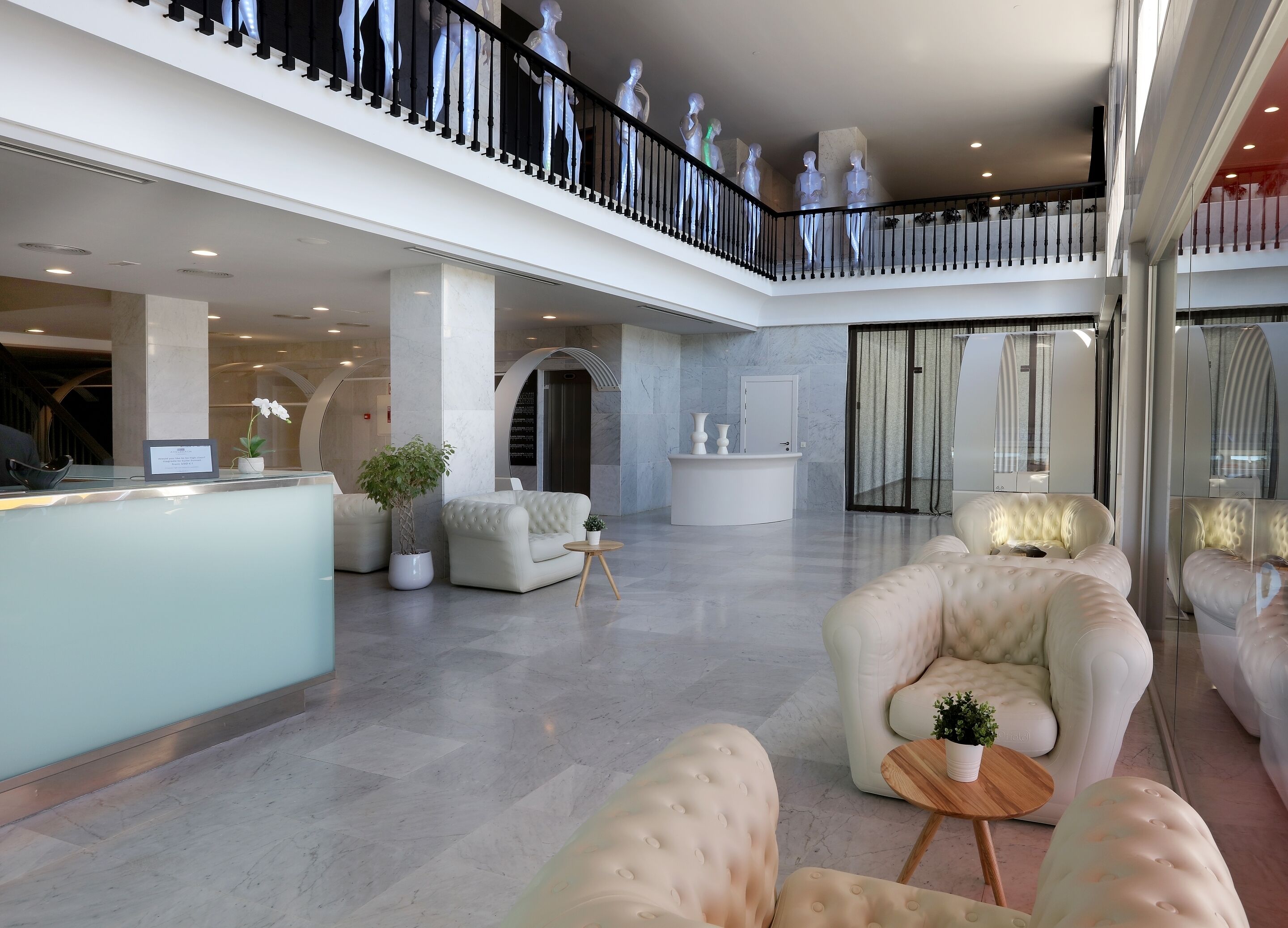 Un'ampia hall con reception, zone relax e un balcone con statue decorative.