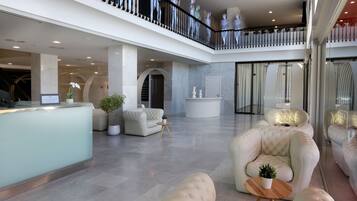 Un'ampia hall con reception, zone relax e un balcone con statue decorative.