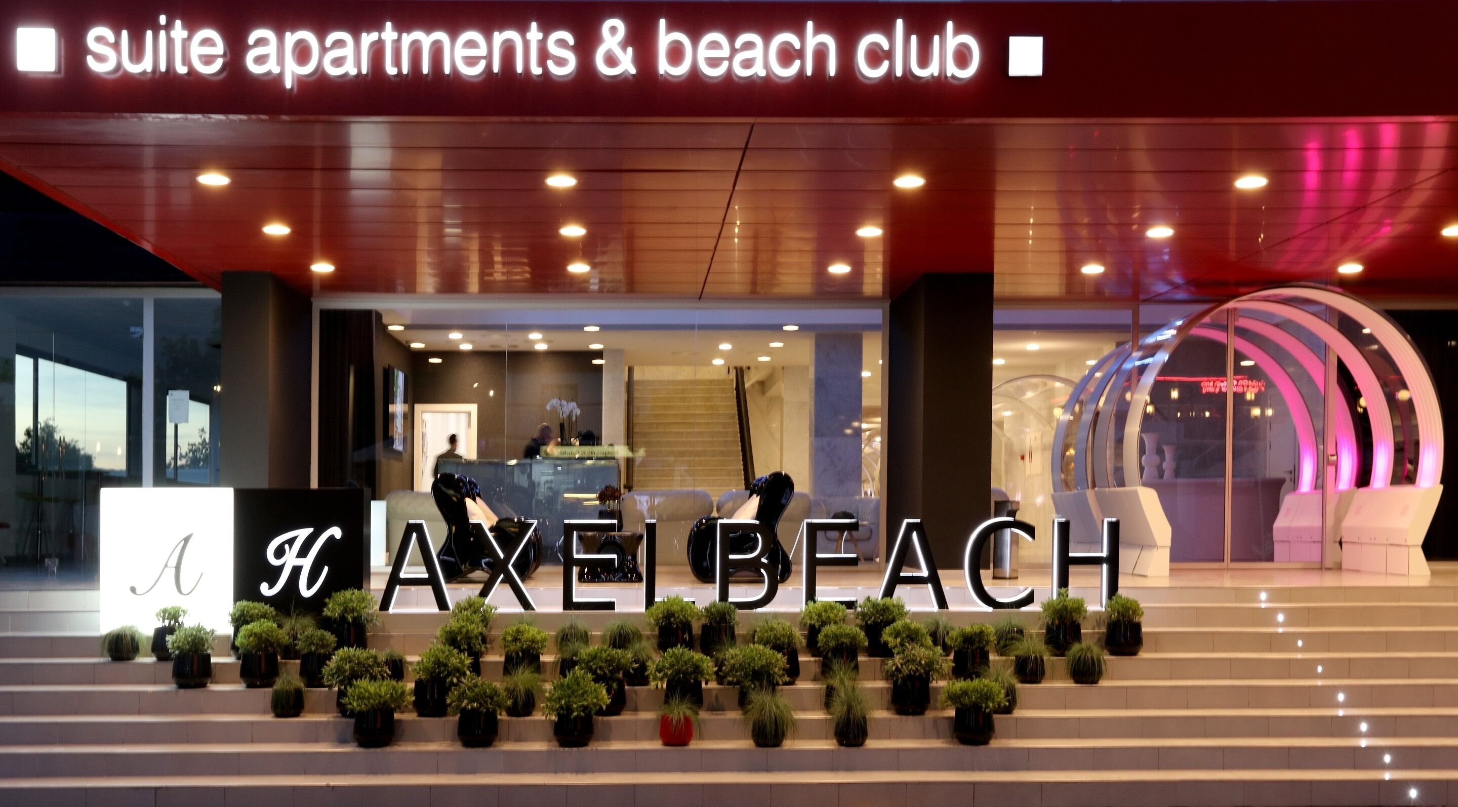 A hotel entrance with a sign reading "suite apartments & beach club".
