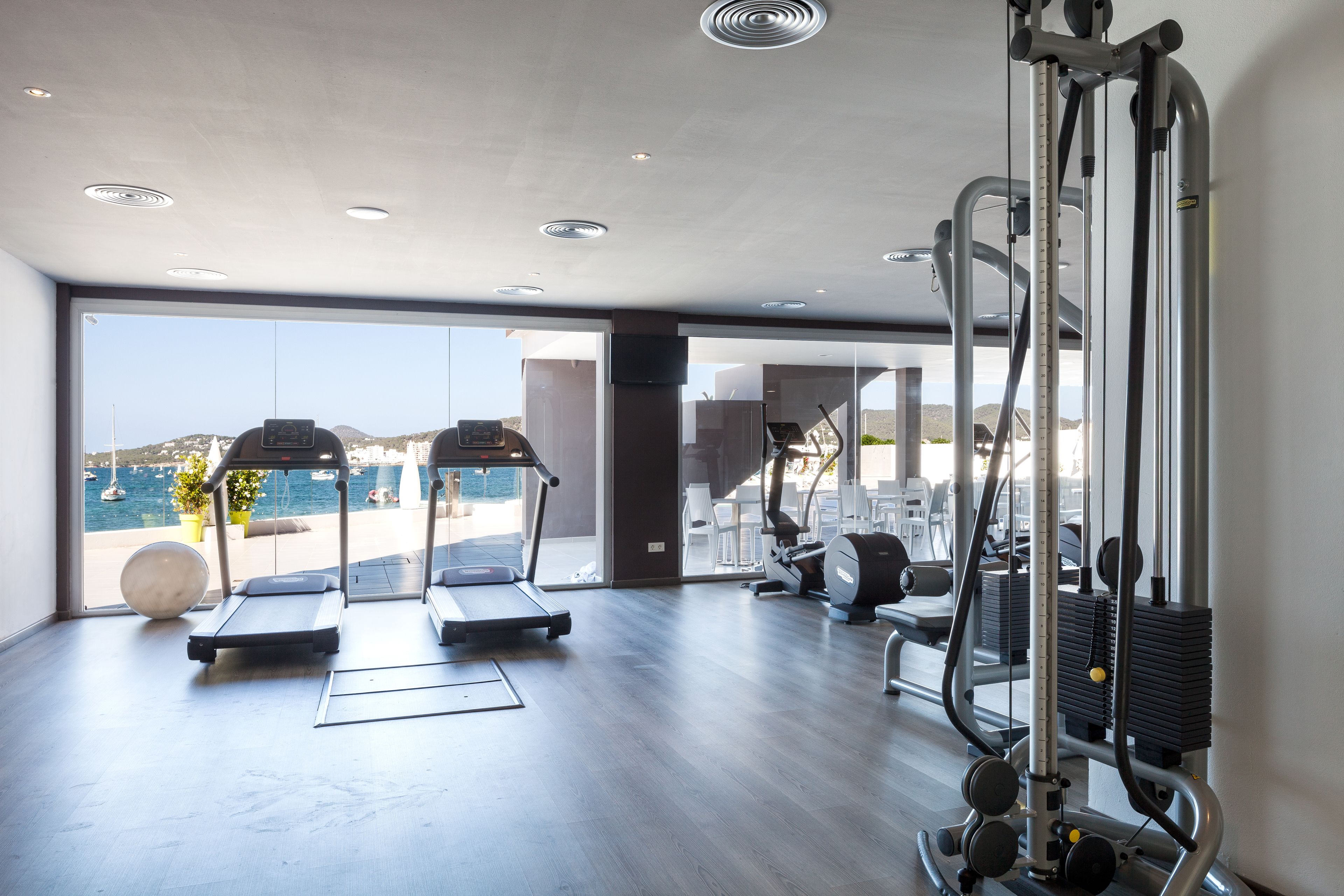 Une salle de sport moderne équipée de tapis de course, de machines de musculation et dotée d’une grande fenêtre donnant sur un paysage magnifique.