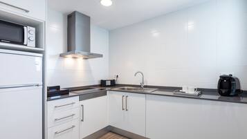 A modern kitchen with white cabinets, a stainless steel sink, a microwave, and a coffee maker.