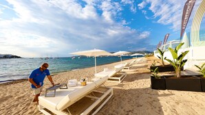 A beachside hotel with sun loungers, umbrellas, and a view of the sea. - Axel Beach Ibiza - Adults Only (Sant Josep de sa Talaia)