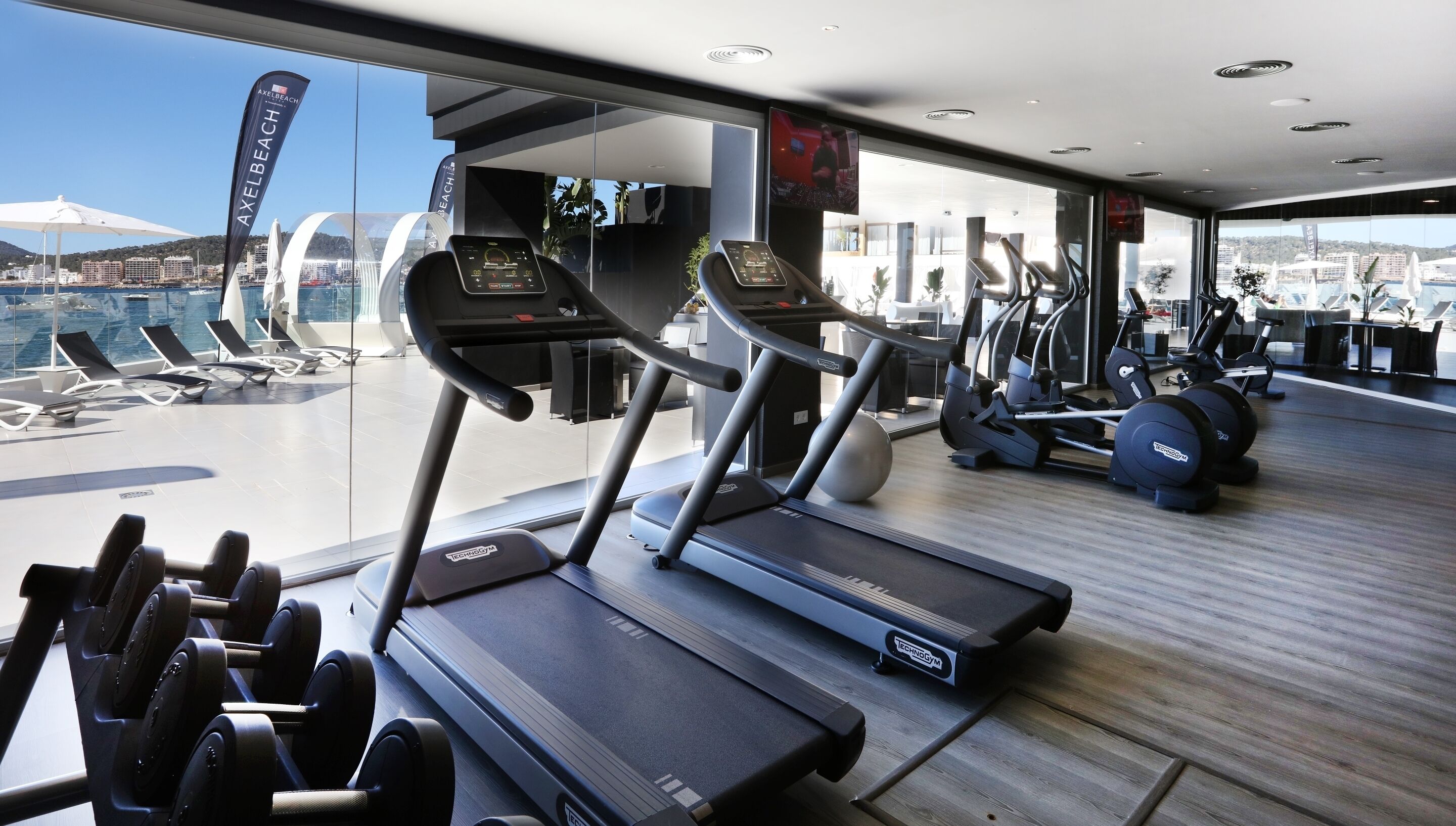 Une salle de sport moderne équipée de tapis de course, de vélos elliptiques et de bancs de musculation.