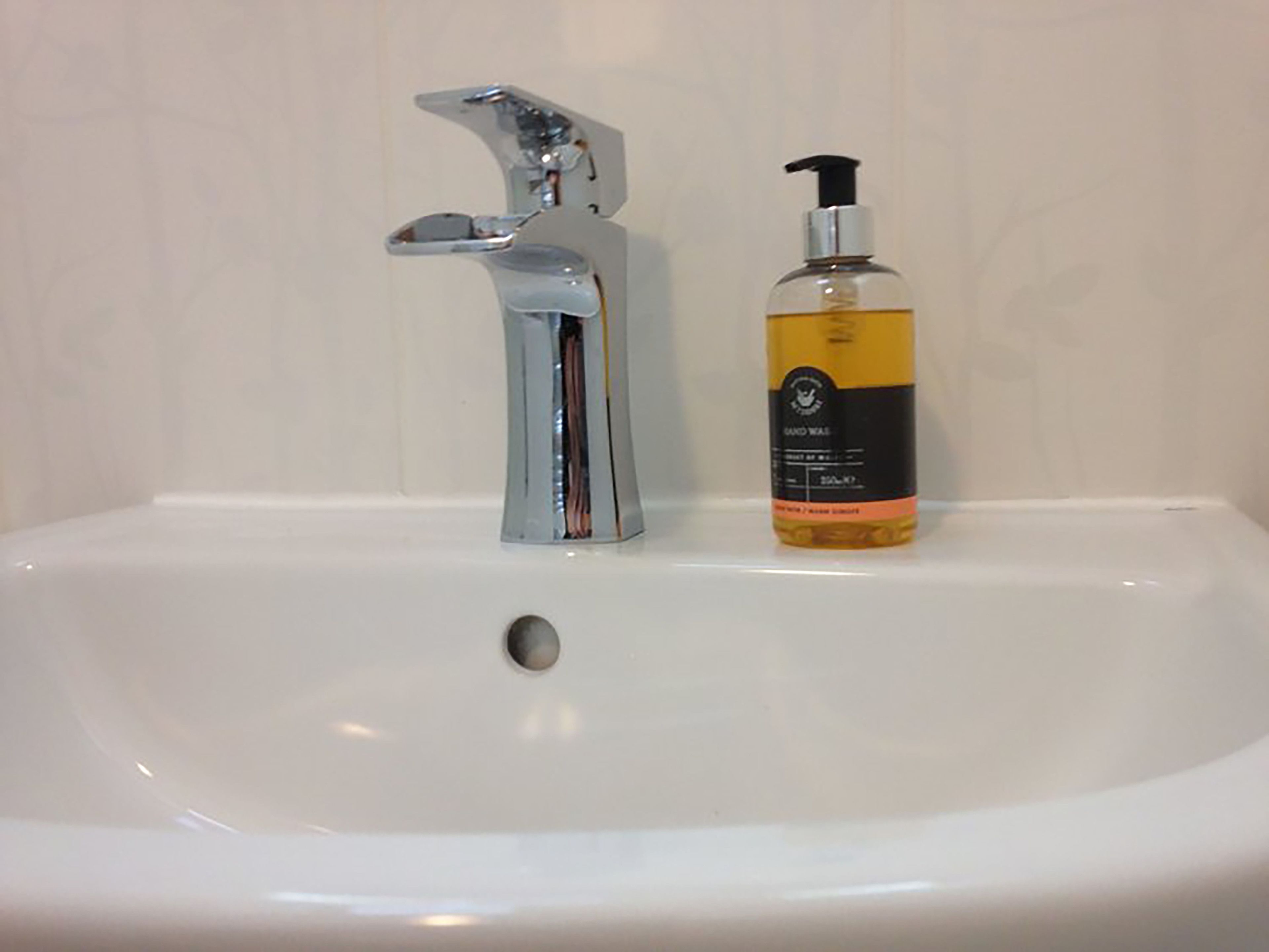 A bathroom sink with a chrome faucet and a bottle of hand soap.