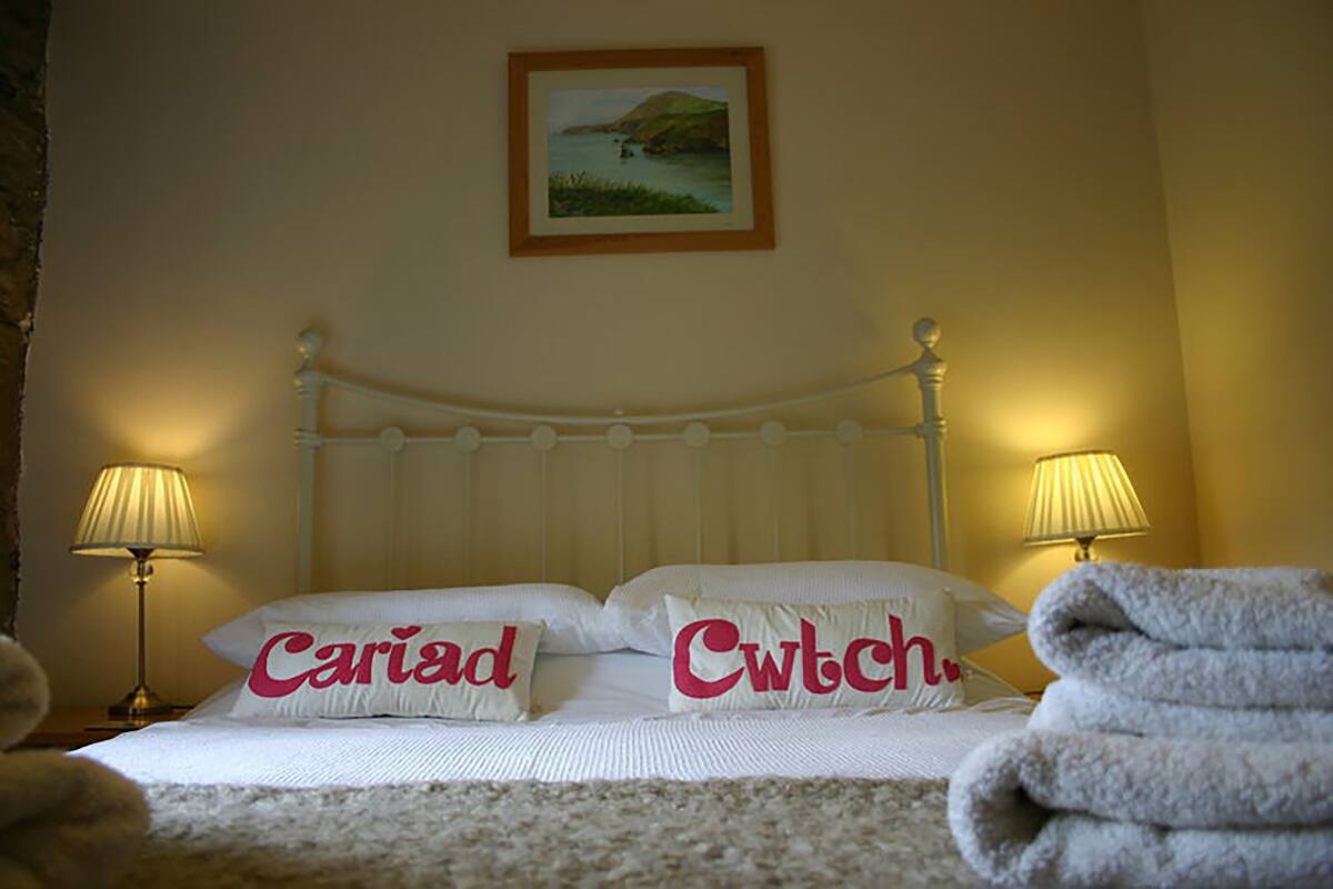 A neatly made bed with two pillows, a framed picture on the wall, and two bedside lamps.