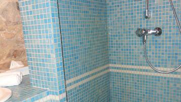 Ein Badezimmer mit blauen Mosaikfliesen, einer Dusche und einem Waschbecken mit Handtuch.
