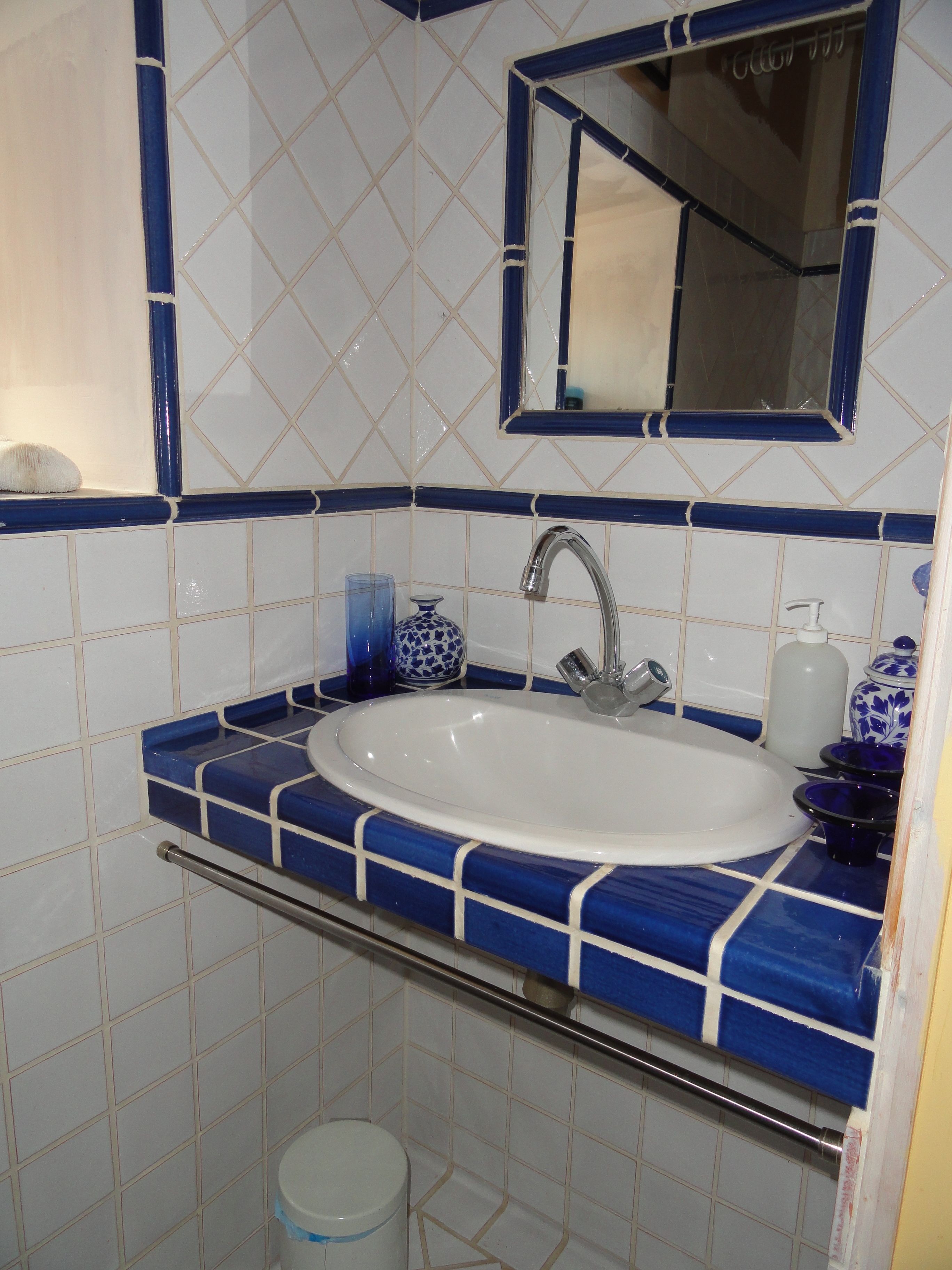 A bathroom with a white sink, blue-tiled walls, and a mirror above the sink.