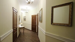 A hallway with wooden doors, a round table with a lamp, and framed pictures on the walls. - Boomerang Business Hotel (Odesa)